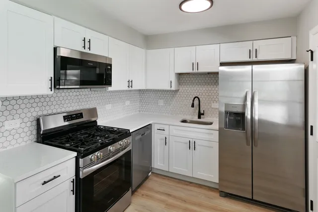 a kitchen with cabinets stainless steel appliances and wooden floor
