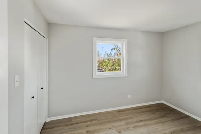 a view of an empty room with wooden floor and closet