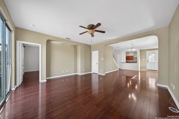 an empty room with wooden floor and fan