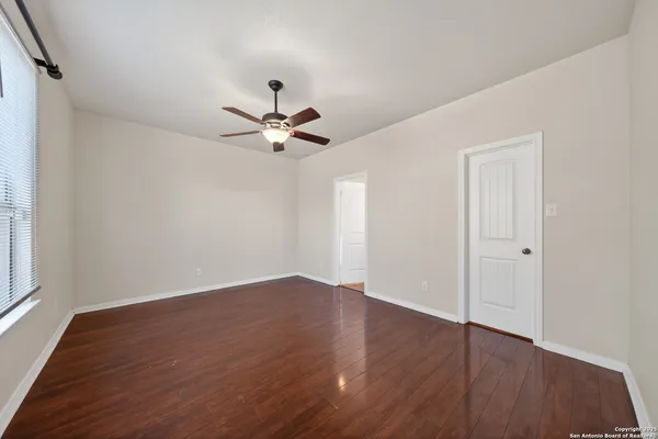 a view of an empty room with wooden floor and a window