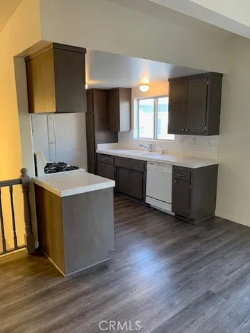 a kitchen with stainless steel appliances a stove a sink a refrigerator wooden floor and cabinets