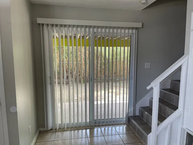 an empty room with wooden floor chandelier fan and windows