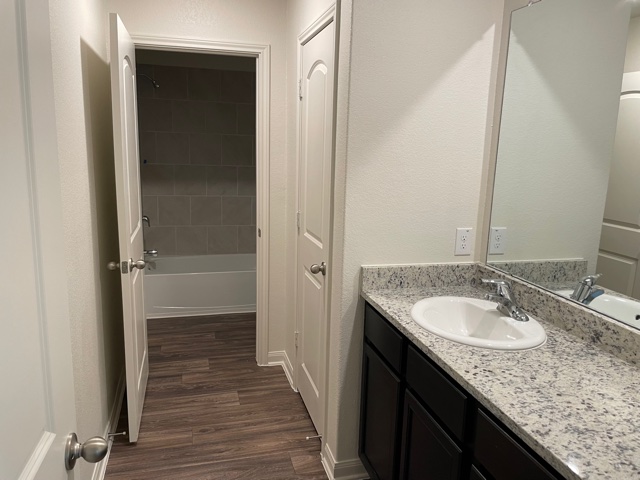 18741 Speculator Lane Elgin, TX 78621 - Photo 20 of 28 Full bathroom featuring vanity, dark wood-style floors, a textured wall, and shower / bathtub combination