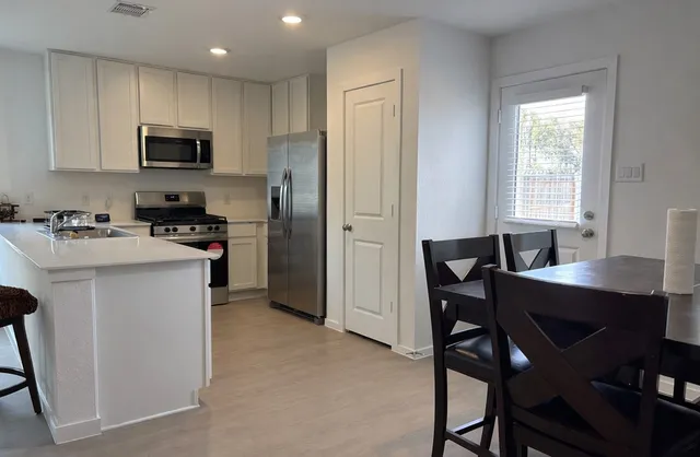 a kitchen with stainless steel appliances a table chairs refrigerator a sink dishwasher and microwave