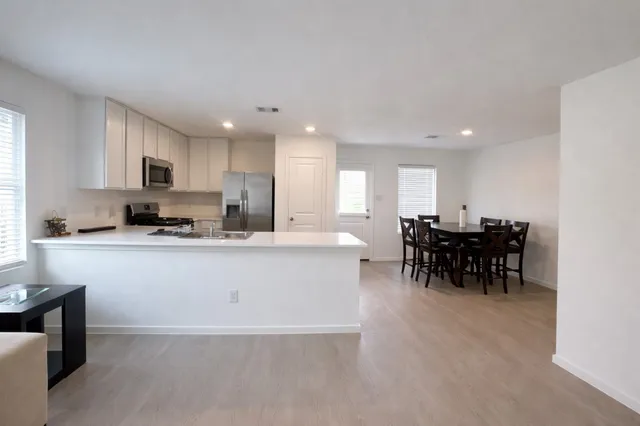 a large white kitchen with lots of counter space and dining table