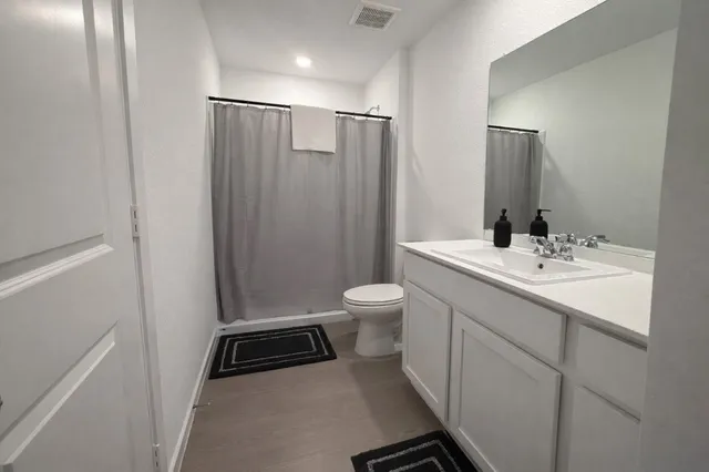 a bathroom with a sink a toilet a mirror and shower