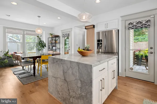 a kitchen with stainless steel appliances granite countertop a table chairs and a refrigerator