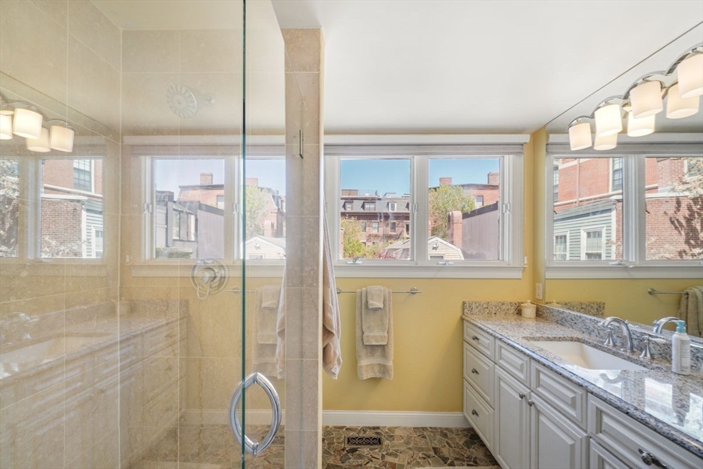 65 Rutherford Avenue Boston, MA 02129 - Photo 12 of 25 a bathroom with a granite countertop double vanity sink a mirror and a shower
