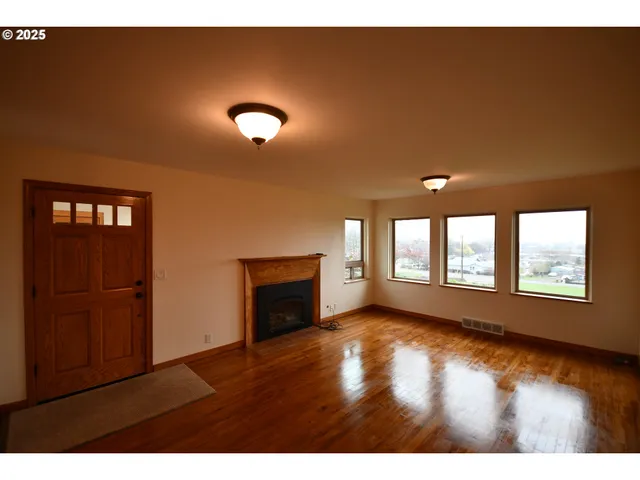 a view of an empty room with a window and wooden floor