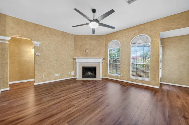 an empty room with wooden floor fireplace and windows