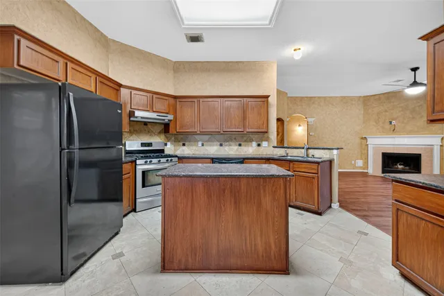 a kitchen with stainless steel appliances granite countertop a stove a sink a refrigerator and a microwave