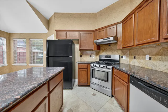 a kitchen with stainless steel appliances granite countertop a refrigerator a stove and a sink