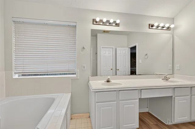 a bathroom with a sink double vanity granite tub shower and a mirror