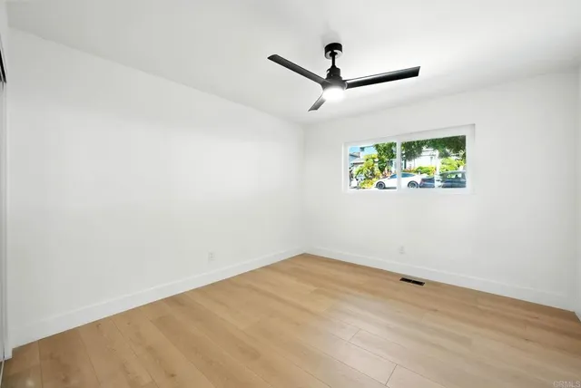 an empty room with a window and a ceiling fan