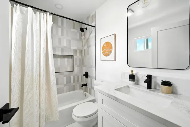 a bathroom with a granite countertop sink a mirror a bathtub and shower