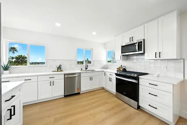 a kitchen with granite countertop white cabinets and stainless steel appliances