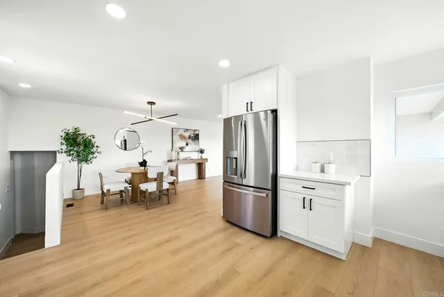 a kitchen with granite countertop a refrigerator a stove a dining table and chairs with wooden floor