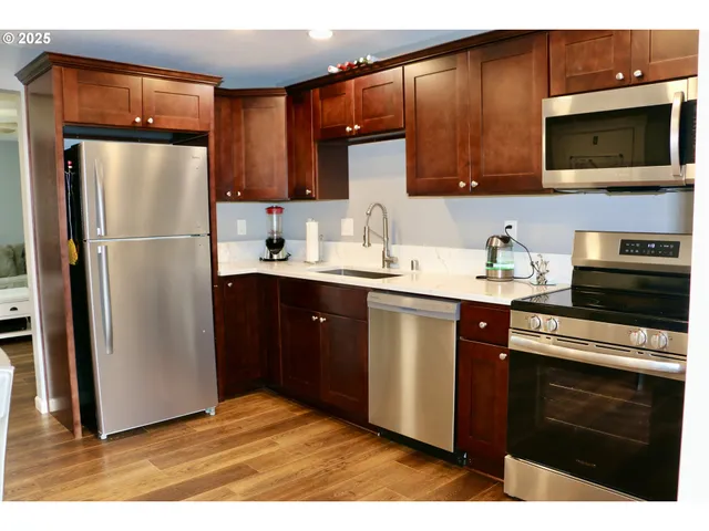 a kitchen with stainless steel appliances granite countertop a refrigerator stove top oven and sink