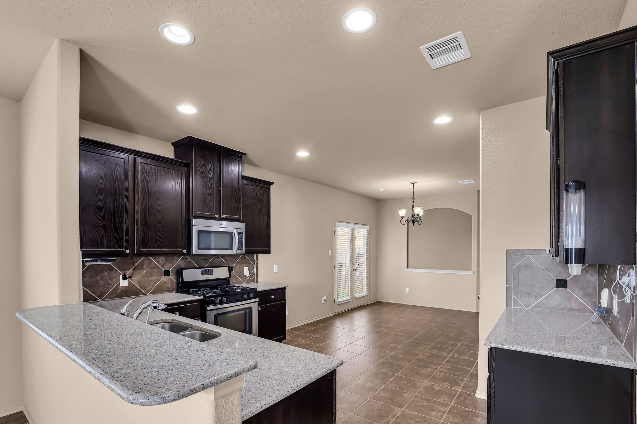 21307 Carleen Creek Trail Spring, TX 77379 - Photo 6 of 25 Modern kitchen with plenty of cabinets, granite countertops, and stainless steel appliances. It opens into the formal dining area with tiled flooring.