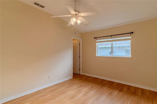 an empty room with wooden floor fan and windows