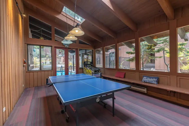 a living room with furniture pool table wooden floor and windows