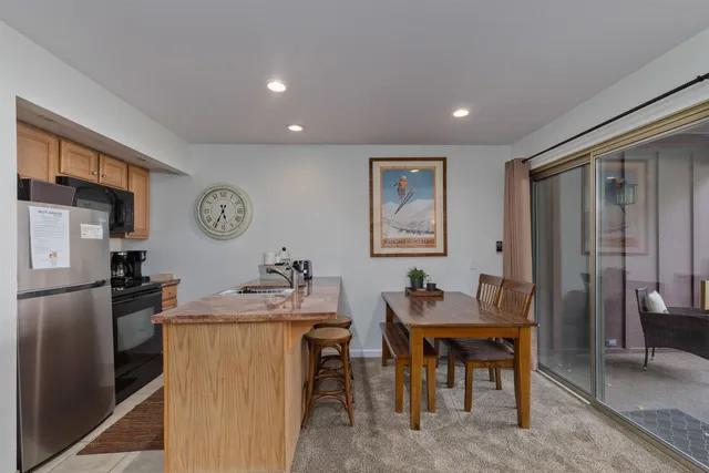 a dining hall with stainless steel appliances granite countertop a dining table and chairs with wooden floor