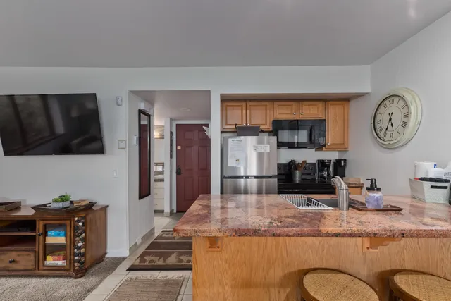 a kitchen with kitchen island granite countertop a refrigerator a stove and a sink with wooden floor