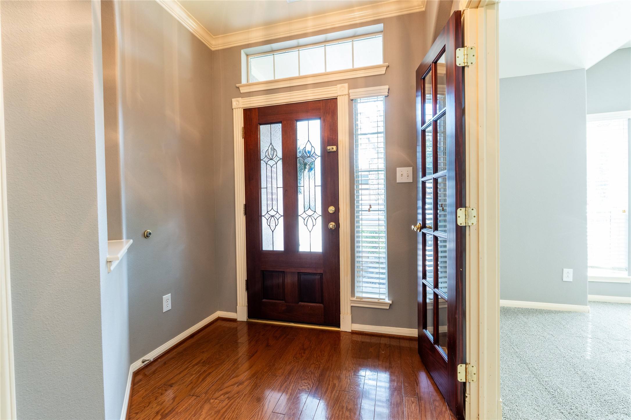 10619 Crownsedge Drive Spring, TX 77379 - Photo 29 of 38 Bright entryway with elegant wood flooring, decorative glass front door, and French doors leading to an adjacent room. Natural light fills the space through a transom window and side panels.