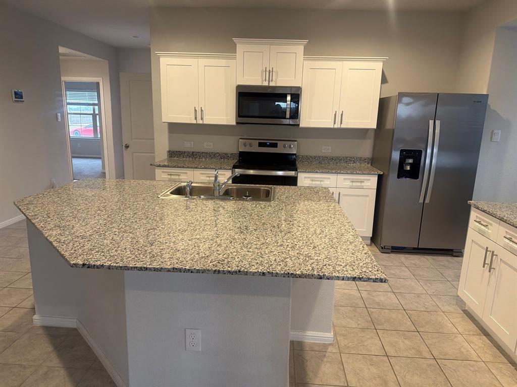 721 Durango Lane Cleburne, TX 76033 - Photo 4 of 25 a kitchen with granite countertop a refrigerator a stove and microwave