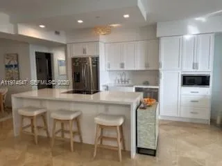 a kitchen with stainless steel appliances granite countertop a table chairs refrigerator and sink