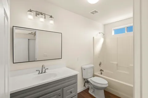 a bathroom with a double vanity sink toilet mirror and shower