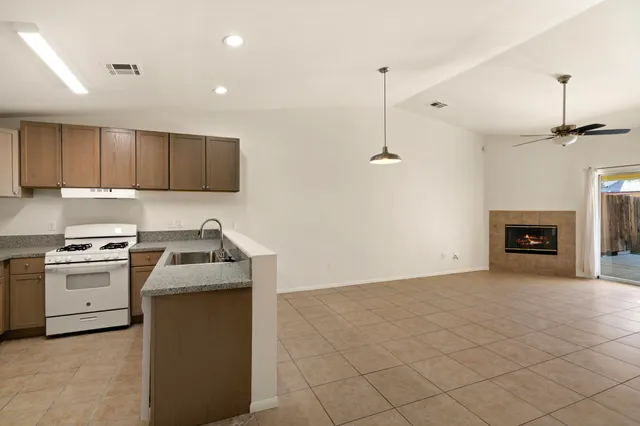 a kitchen with granite countertop a sink a stove and a refrigerator