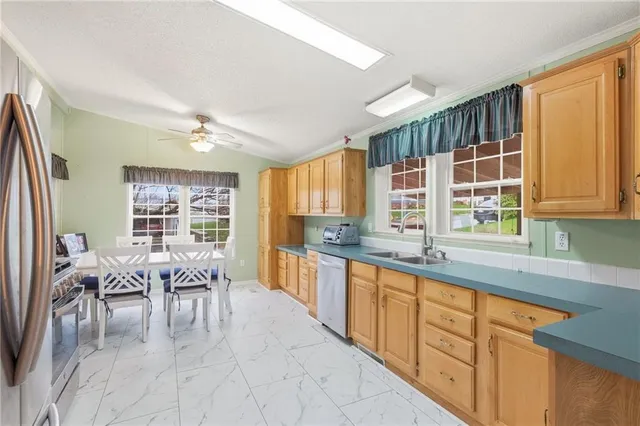 a large white kitchen with granite countertop a stove a sink a dining table and chairs