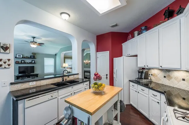 a kitchen with stainless steel appliances kitchen island granite countertop a stove refrigerator and cabinets