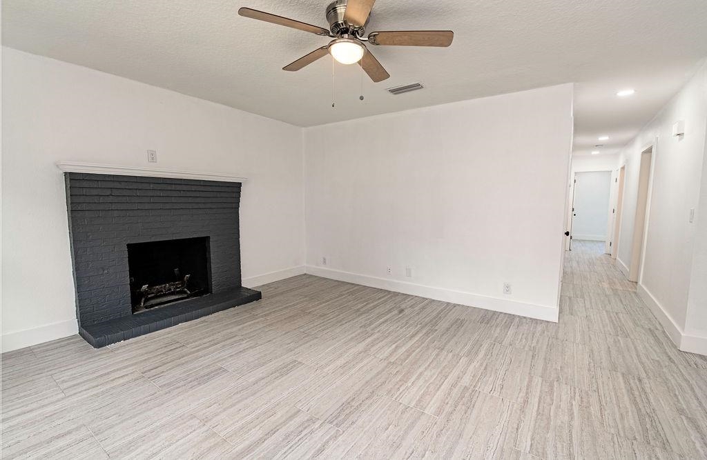 149 Pompano Road St. Augustine, FL 32086 - Photo 7 of 35 a view of an empty room with wooden floor a fireplace and a ceiling fan