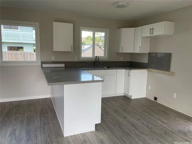 a kitchen with granite countertop white cabinets and wooden floor