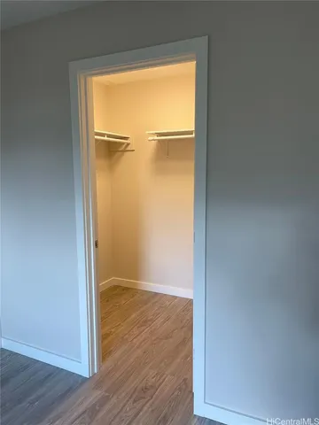 an empty room with wooden floor closet and windows