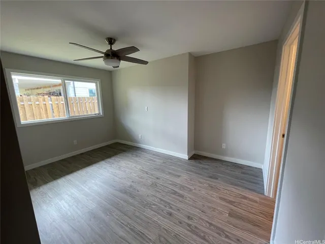 an empty room with wooden floor fan and windows