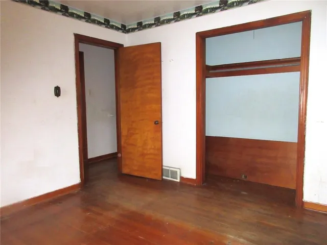 a view of an empty room with closet and wooden floor