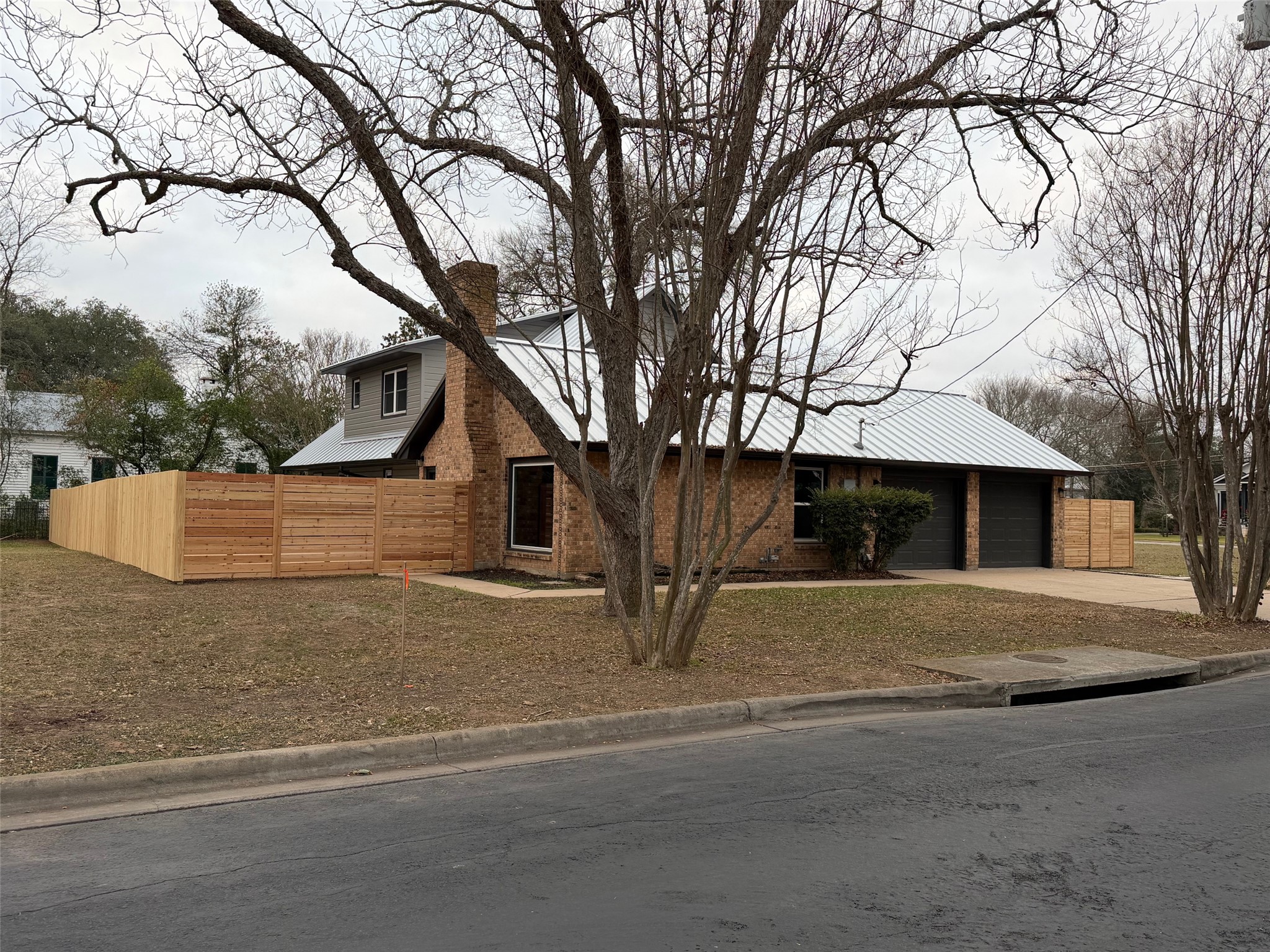 503 Elm Street Bastrop, TX 78602 - Photo 25 of 27 View of front facade with concrete driveway, brick siding, a chimney, and an attached garage