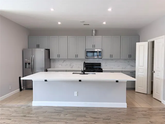 a kitchen with stainless steel appliances a refrigerator sink and white cabinets