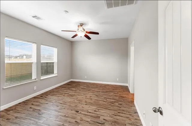 a view of an empty room with a window and wooden floor
