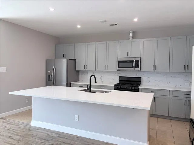 a kitchen with stainless steel appliances a refrigerator sink stove and white cabinets