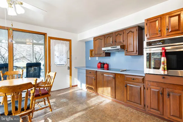 a kitchen with stainless steel appliances kitchen island granite countertop a table chairs in it and a window