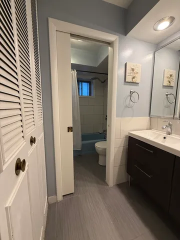 a spacious bathroom with a double vanity sink a toilet and a mirror