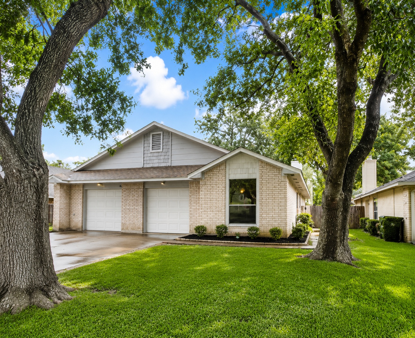 2114 Redwing Way Round Rock, TX 78664 - Photo 2 of 8 Cream brick exterior featuring two garage bays, a large front window, and a landscaped front garden bed