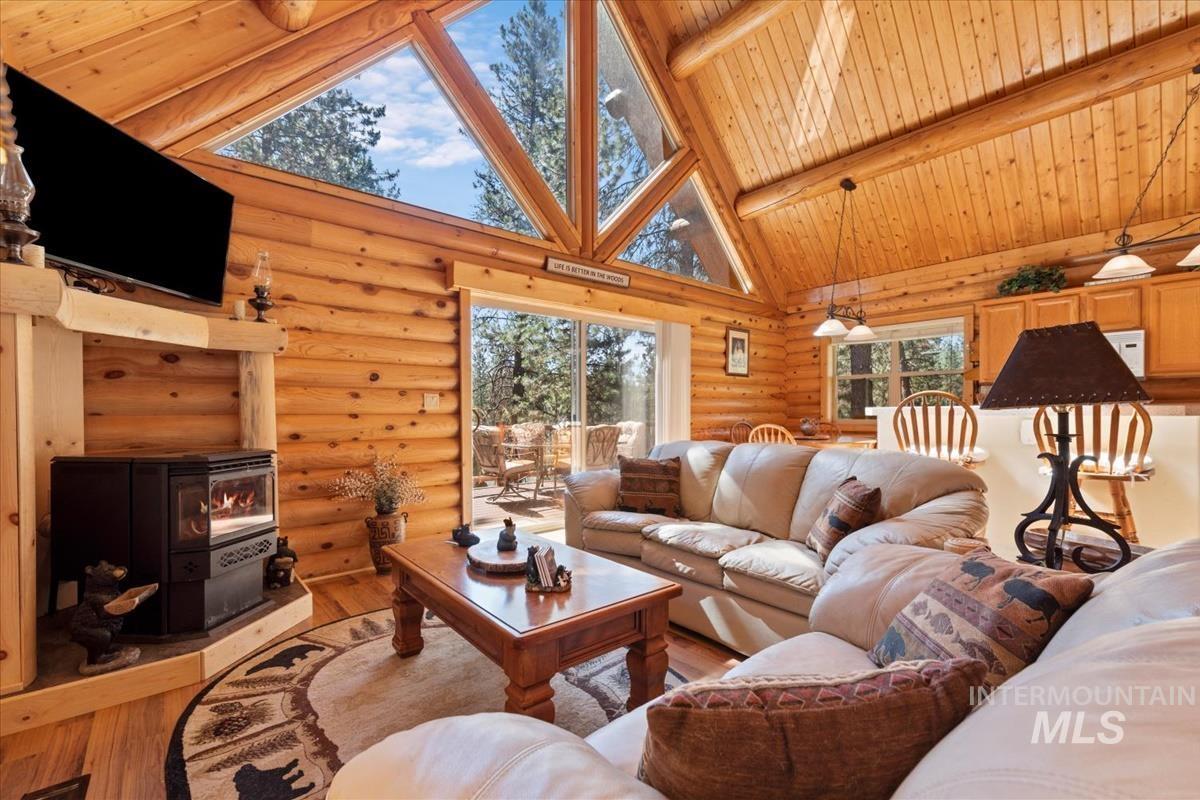 10 Elk Point Road Garden Valley, ID 83622 - Photo 11 of 42 Living area featuring a wood stove, hardwood / wood-style floors, log walls, and a high wooden beamed ceiling