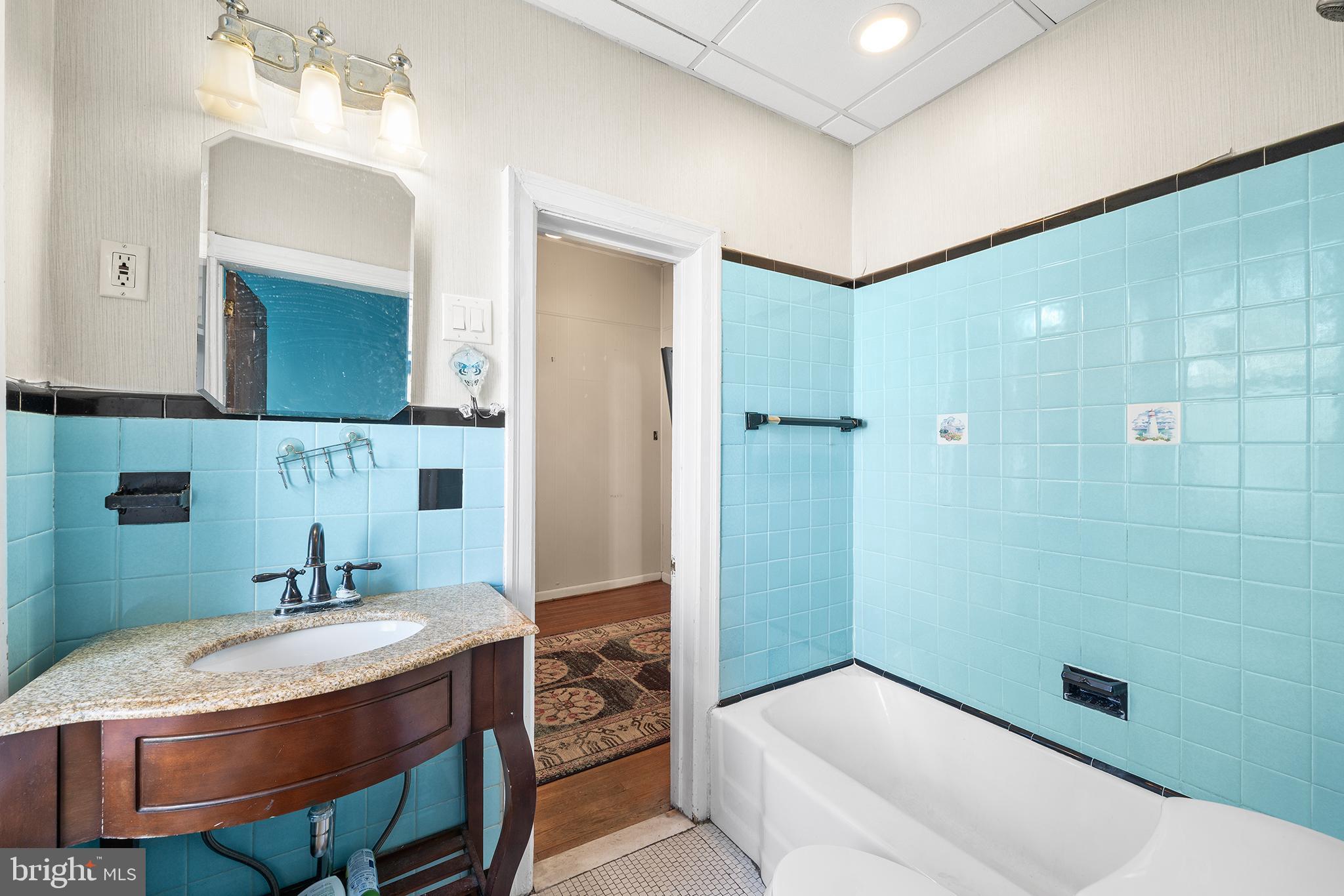 7301 Chestnut Avenue, Unit 1 Elkins Park, PA 19027 - Photo 12 of 22 a bathroom with a granite countertop sink a mirror and a bathtub