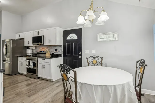 a kitchen with a refrigerator a stove a microwave a dining table and chairs