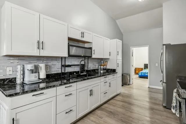 a kitchen with stainless steel appliances a sink a stove a refrigerator a center island and cabinets